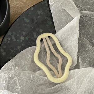 Detail view of wave-shaped yellow hair clip with soft flocked texture on minimalist background