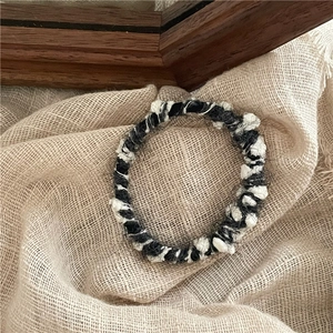 Détail de l'élastique à cheveux en tweed noir et blanc avec texture tissée douce