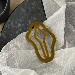 Detail view of mustard yellow flocked hair clip with an organic wavy oval shape