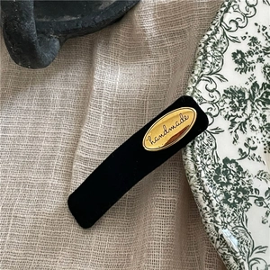Detailed macro shot of vintage black velvet hair clip with golden handmade letter label