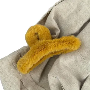 Large ginger yellow plush hair claw clip in soft faux fur on a beige linen background