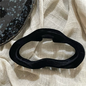 Macro shot of black flocked wave geometric claw clip on a soft textured linen background