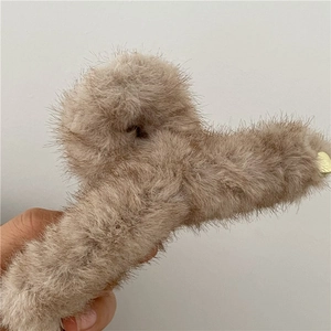 Dettaglio della molletta in peluche con ciondolo a cuore dorato per acconciature eleganti