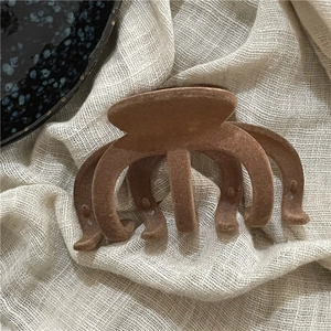 Detail of flocking wave pattern hair claw clip with dark brown velvet texture finish