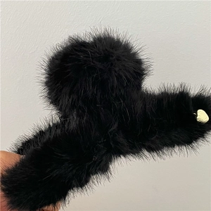 Dettaglio della molletta per capelli in pelliccia nera con cerniera in metallo dorato