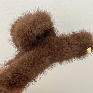 Dettaglio della molletta per capelli in peluche marrone scuro con ciondolo a cuore oro