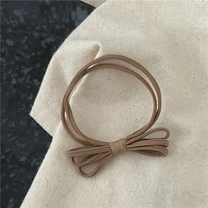 Vue détaillée d'un chouchou à nœud marron café sur une surface texturée minimaliste