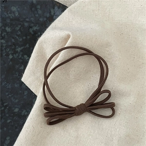 Gros plan d'un chouchou élastique marron avec nœud multicouche sur une texture en lin