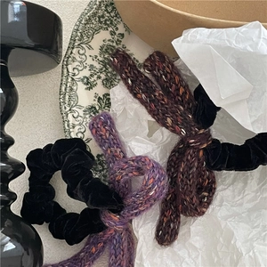 Detail of velvet scrunchie and hand-knit wool bow hair ties in vintage autumn colors