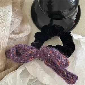 Detailed view of hand-knitted purple mixed-color bow tie with black velvet hair tie