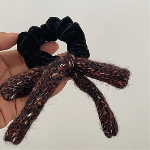 Close-up of black velvet hair tie with a colorful textured knitted bow accessory