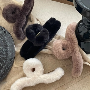 Plush hair claws in four colors including brown, black, and beige on a linen backdrop