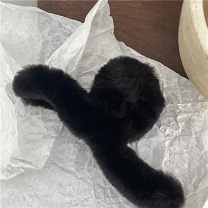Close-up of large black faux fur hair claw clip with fluffy texture for autumn and winter
