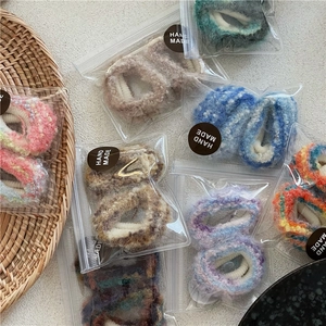 Dettaglio di elastici per capelli in peluche colorati in confezione artigianale su superficie