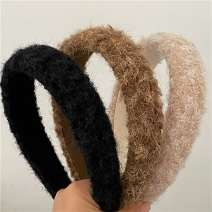 Detailed close-up of soft faux fur headbands in black, beige, and brown textures