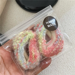 Dettaglio di elastici per capelli in maglia colorata con etichetta fatta a mano