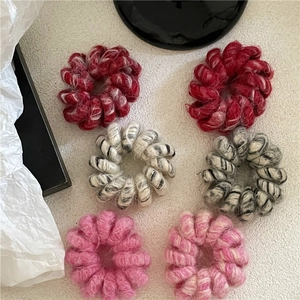 Détail des élastiques à cheveux spirale en laine pelucheuse tons rouge et rose