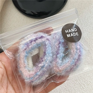 Dettaglio di due elastici per capelli morbidi fatti a mano in viola e blu