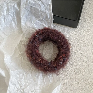 Detail of dark coffee plush scrunchie with subtle colorful fibers on white texture