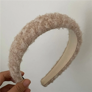 Close-up of khaki plush fleece headband showing the thick curly wool texture and inner lining