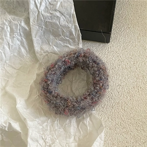 Detail of plush mixed-fabric hair scrunchie with granular texture on white paper