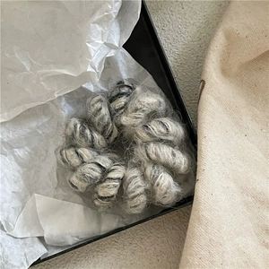 Vue détaillée de la texture douce en laine grise et beige sur l'élastique à cheveux