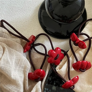 Detail of red floral and heart charms on elastic hair ties with a high-glaze finish