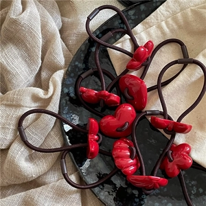 Detail of red heart and bow charms on brown elastic hair ties in a luxury tray