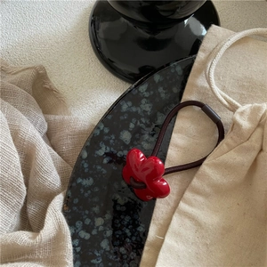Macro shot of a glossy red floral resin charm on a brown elastic hair tie band