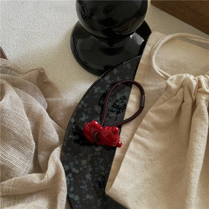 Detailed view of a cute red resin bear hair tie on a minimalist decorative display