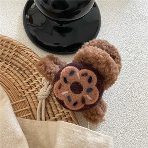 Détail d'une pince à cheveux en peluche marron avec fleur en feutre et touches bleues