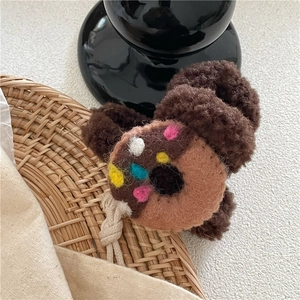 Détail d'une pince à cheveux en peluche marron avec motif donut en feutrine