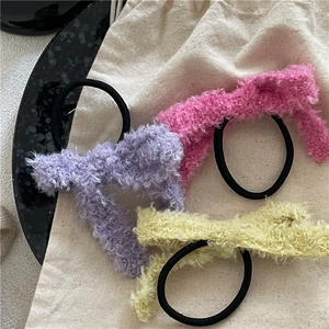 Gros plan de chouchous nœuds en peluche rose et violet sur un sac en lin rustique