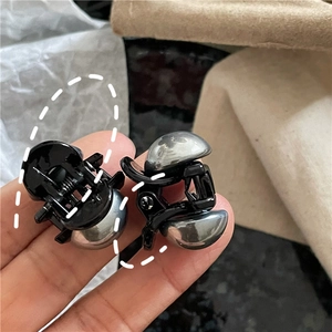 Dettaglio di mini mollette per capelli nere con perle argentate per acconciature laterali