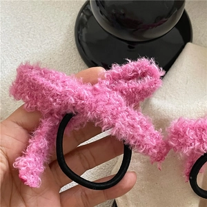 Gros plan sur l'élastique à cheveux rose en peluche avec texture douce et nœud élégant