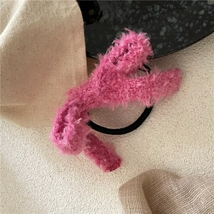 Gros plan d'un chouchou en peluche rose vif avec texture douce en fausse fourrure et élastique