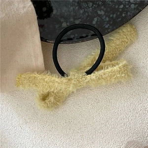 Détail d'un chouchou en peluche jaune avec nœud et élastique noir de haute élasticité
