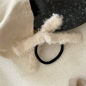 Gros plan du chouchou en peluche crème avec nœud et bande élastique noire pour l'hiver
