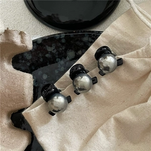 Set di tre mini mollette per capelli nere con perle grigio metallizzato su fondo beige