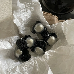 Mini mollette per capelli nere minimaliste con borchie argentate su carta stropicciata
