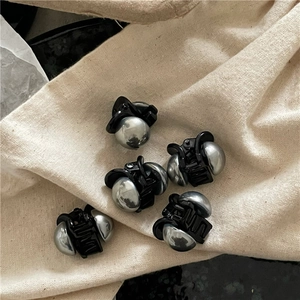 Dettaglio ravvicinato di cinque mini mollette nere con perline metalliche color argento
