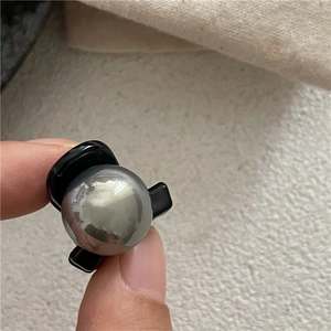 Dettaglio di una piccola clip per capelli nera con una decorazione a sfera in metallo