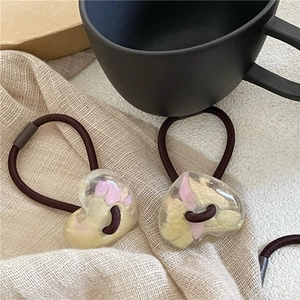 Vue détaillée des breloques cœur en résine avec inserts floraux sur des élastiques à cheveux