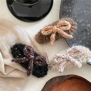 Détail de trois barrettes à cheveux en laine tricotée marron, noir et beige