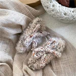 Détail de barrettes à cheveux nœud en tricot beige avec texture douce en fil bouclé