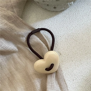 Détail de la perle en résine en forme de cœur crème sur un élastique à cheveux marron