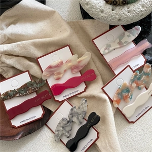 Détail de pinces à cheveux ondulées en acétate coloré avec texte Amy Bear doré