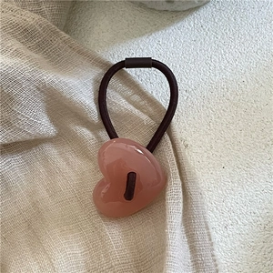 Vue détaillée du pendentif cœur rose sur un élastique à cheveux marron souple