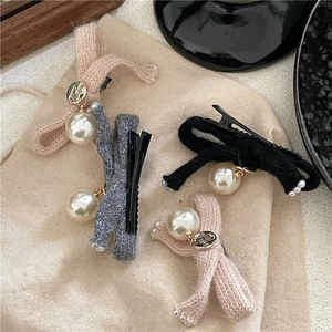 Detailed view of knitted bow hair clips with pearls and vintage gold metal buttons