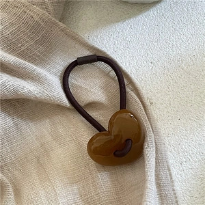 Détail d'une perle en cœur marron brillant sur un élastique à cheveux extensible